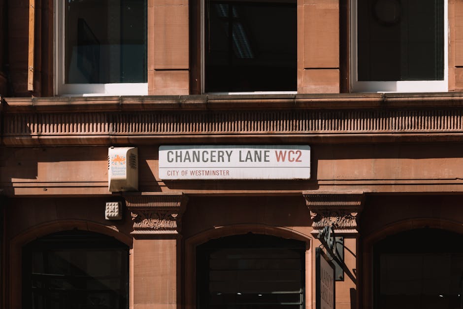 A close-up view of a building facade on Chancery Lane in Westminster, featuring a white street sign with black and red lettering indicating 'Chancery Lane WC2' and 'CITY OF WESTMINSTER.' The building 